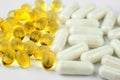 Pills of two types. Yellow fish oil capsules and white vitamin complex capsules