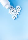 Pills of vitamin in the shape of heart with the opened white plastic container on soft blue background Royalty Free Stock Photo