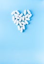 Pills of vitamin in the shape of heart on soft blue background Royalty Free Stock Photo
