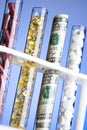 Pills, vitamins and money in test tubes