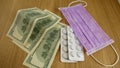 Pills in white plastic, medical masks and dollars on the table. Royalty Free Stock Photo