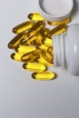 Pills of yellow color are poured on a white surface from plastic jars. View from above.