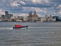 A Pilot boat passes the front of the historic Three Graces buildings on the UNESCO listed Liverpool waterfront on the River Mersey
