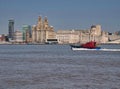 A pilot boat passes the front of the historic Three Graces buildings on the UNESCO listed Liverpool waterfront on the River Mersey