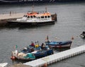 Pilot boats used to guide cruise ships into the harbor moored on the jetty at funchal docks with men working fishing boats nearby