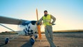 A pilot is standing beside a cropduster on a runway in an open field