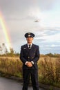 Pilot stands on runway rainbow nature landing plane behind