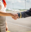 Pilot and stewardess shaking hands.