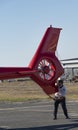 Pilot supporting a helicopter tail rotor as it is being pushed into a hangar.