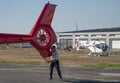 Pilot supporting a helicopter tail rotor as it is being pushed into a hangar.