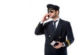 pilot in uniform with passport and ticket in hand talking on smartphone Royalty Free Stock Photo