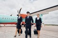 Pilot in uniform and two stewardess is outdoors near plane Royalty Free Stock Photo
