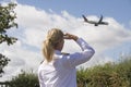 Pilot in uniform watching a passenger jet in the sky