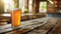 Pilsner beer with frothy head in glass on wooden table, man pouring, blurred background, text space.