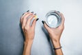 Hands of caucasian girl with yellow pill in left palm and glass of water in right hand.