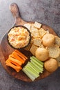 Pimento cheese is a versatile, creamy dip served with vegetables and crackers closeup on the wooden board on the table. Vertical