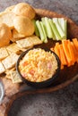 Pimento cheese is a versatile, creamy dip served with vegetables and crackers closeup on the wooden board on the table. Vertical