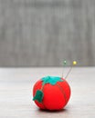 A pin cushion shaped as a red tomato with straight pins