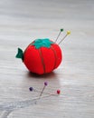 A pin cushion shaped as a red tomato with straight pins
