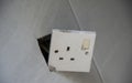 3-pin plug socket adapter hanging out from the wall Royalty Free Stock Photo