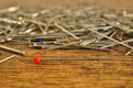 Pin with a red top on the top of the heap of many silver pins used in clothing garment industry