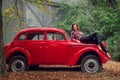 Pin-up girl in jeans and a plaid shirt is posing on a russian red retro car. Royalty Free Stock Photo