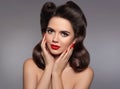 Pin up hairstyle. Beautiful 50s girl holding her cheeks with red