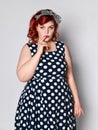 Pin up redhead woman . Beautiful retro female in polka dot dress with red lips and manicure nails and old fashion hairstyle