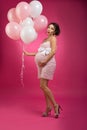 Pin Up retro studio shot of a pregnant woman with balloons. Photo taken in the studio on a pink, bright background