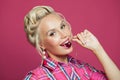 Pin-up woman biting cherry on vibrant pink Royalty Free Stock Photo