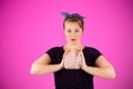 Pin-up woman portrait with bright colors and beautiful make-up in front of a pink background holding a purse in her hands. Royalty Free Stock Photo