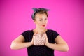 Pin-up woman portrait with bright colors and beautiful make-up in front of a pink background holding a purse in her hands. Royalty Free Stock Photo