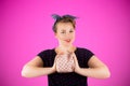 Pin-up woman portrait with bright colors and beautiful make-up in front of a pink background holding a purse in her hands. Royalty Free Stock Photo