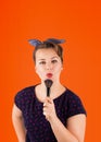 Pin-up woman portrait with bright colors in front of a burnt orange background holding a make-up brush in her hands Royalty Free Stock Photo