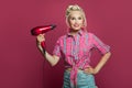 Pin-up woman using hairdryer posing on pink background Royalty Free Stock Photo