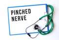 PINCHED NERVE text on a medical folder and stethoscope on white background