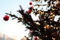 A pine branch decorated with string lights glows warmly against a soft evening sky and festive tree backdrop. Concept peaceful Royalty Free Stock Photo