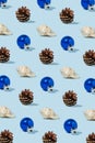 Pine cone, seashell and Christmas ornament ball on blue pastel background. Minimal Christmas at the sea concept. Christmas pattern