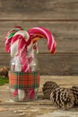 Pine cones and candy cane in jar against wooden plank Royalty Free Stock Photo