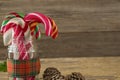 Pine cones and candy cane in jar against wooden plank Royalty Free Stock Photo