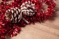 Pine cones and red christmas tinsel on wooden background Royalty Free Stock Photo