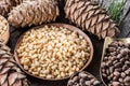 Pine nuts in the bowl and pine nut cones on the wooden table. Organic food Royalty Free Stock Photo