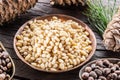 Pine nuts in the bowl and pine nut cones on the wooden table. Organic food. Top view Royalty Free Stock Photo