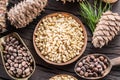 Pine nuts in the bowl and pine nut cones on the wooden table. Organic food. Top view Royalty Free Stock Photo