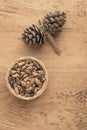 Pine nuts, kernels and cone on wooden table