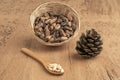 Pine nuts, kernels and cone on wooden table