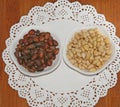 Pine nuts are laid out in white plates Next to brown and beige pine nuts on a white napkin and a wooden Board. Royalty Free Stock Photo