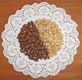 Pine nuts are laid out in white plates Next to brown and beige pine nuts on a white napkin and a wooden Board. Royalty Free Stock Photo