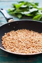 Pine nuts in pan and basil leaves