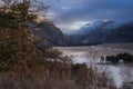 Pine tree and dry grass on the background of a river with a road through a mountain valley at winter dawn in the Altai mountains Royalty Free Stock Photo